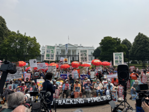 A large crowd of people in front of the White House with many signs that say "no fossil fuels," and "no fracking pipelines," and etc.